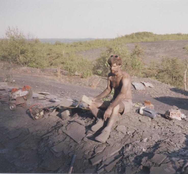 Jon covered in black dirt from a day of cutting the shale with a diamond saw which is shown to his right. PMG St. Clair site 1991